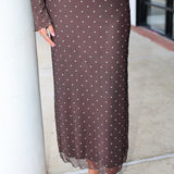 A smiling blonde woman wearing the Amara brown long-sleeve V-neck top with white polka dots by Z Supply and a tie-front detail, paired with a matching brown mesh midi Eda polka-dot skirt at Rodeo Boutique.