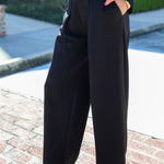 Person wearing black high-waisted pants and a striped shirt outdoors.