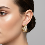 Gold huggie hoop earrings with textured horizontal ridges and small clear stones, displayed on a pink card labeled 'Rodéo BOUTIQUE'.
