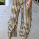 Person wearing striped pants and gold shoes on a sidewalk.