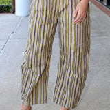 Person wearing striped pants and gold shoes on a sidewalk.