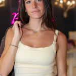 Cream-colored tank top with small scalloped trim and dark brown pants, 