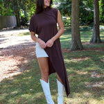 A woman tailgating at LSU  wearing a dark brown high-low cape top, a white mini skirt, and white cowboy boots.