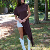 A woman tailgating at LSU  wearing a dark brown high-low cape top, a white mini skirt, and white cowboy boots.