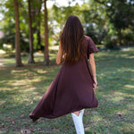 A woman tailgating at LSU  wearing a dark brown high-low cape top, a white mini skirt, and white cowboy boots.