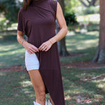A woman tailgating at LSU  wearing a dark brown high-low cape top, a white mini skirt, and white cowboy boots.