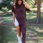 A woman tailgating at LSU  wearing a dark brown high-low cape top, a white mini skirt, and white cowboy boots.
