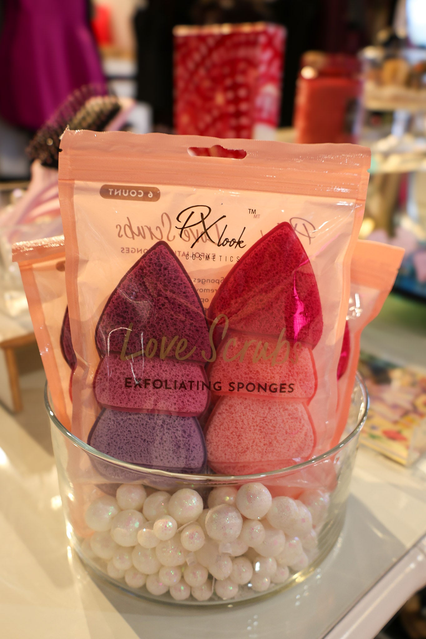 Exfoliating sponges in a glass container with visible brand name on a blurred background