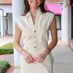 Woman wearing a beige dress standing outdoors with a building in the background