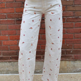 Person wearing a white outfit with floral patterns against a brick wall.
