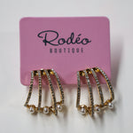 Pair of gold and pearl earrings on a pink card with 'Rodeo Boutique' branding.