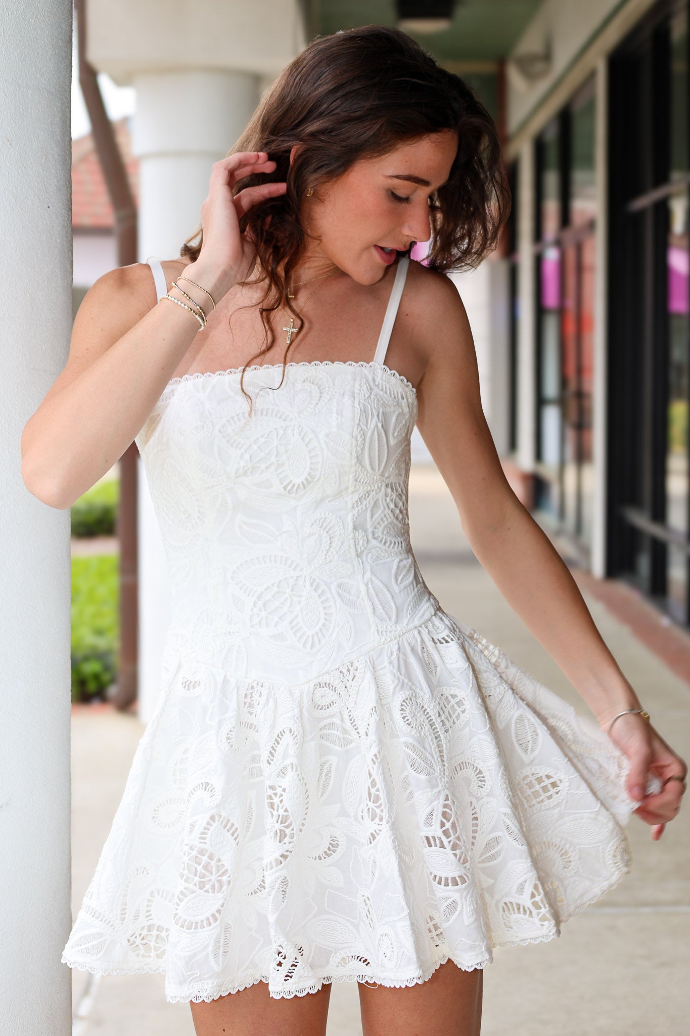 Woman wearing a white eyelet lace dress standing outdoors.