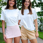 Two women standing on a path with trees and water in the background