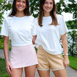 Two women standing on a path with trees and water in the background
