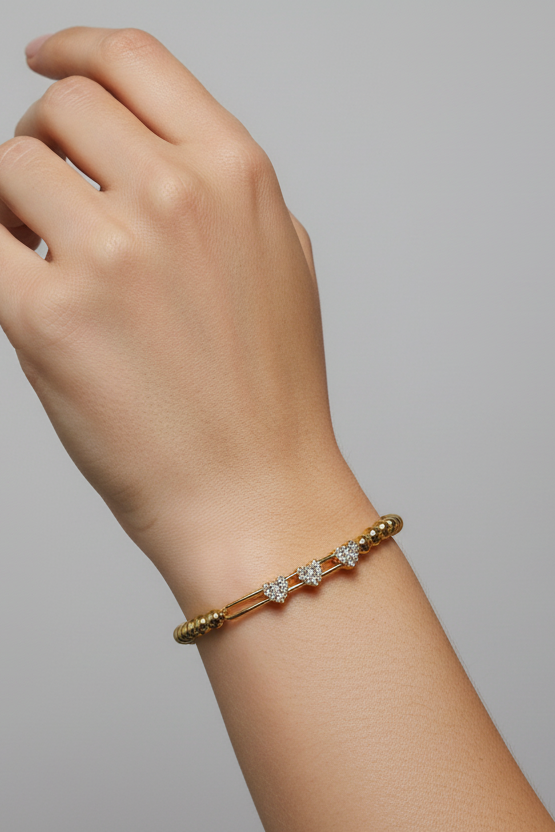 Gold bracelet with diamonds on a wrist against a gray background