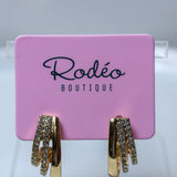 Gold huggie hoop earrings with clear rhinestone accents, displayed on a pink Rodéo Boutique card.