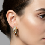 Gold huggie hoop earrings with clear rhinestone accents, displayed on a pink Rodéo Boutique card.