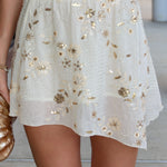 White skirt with gold floral embellishments worn by a person.
