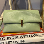 Green handbag on a surface with a magazine underneath