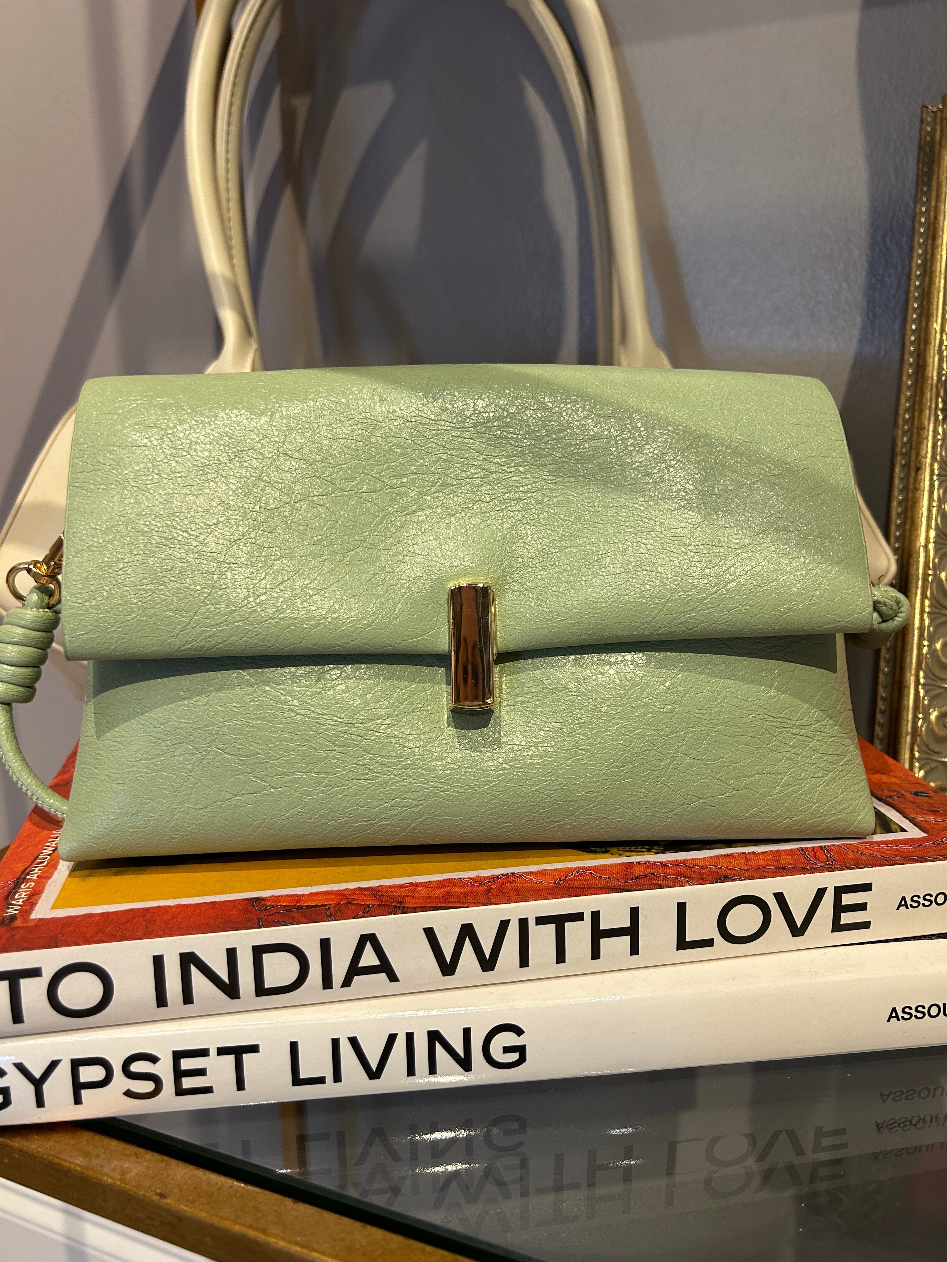 Green handbag on a surface with a magazine underneath