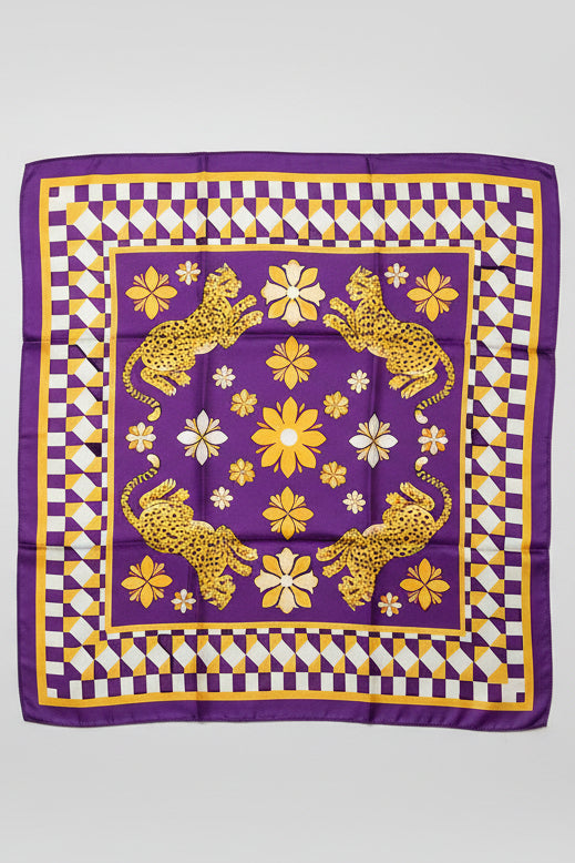 A square purple silk scarf with a gold and white checkered border, featuring four yellow leopards and white flowers in the center