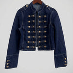 A dark blue denim jacket with decorative gold-colored military-style buttons, shown hanging on a wooden hanger against a white wall.