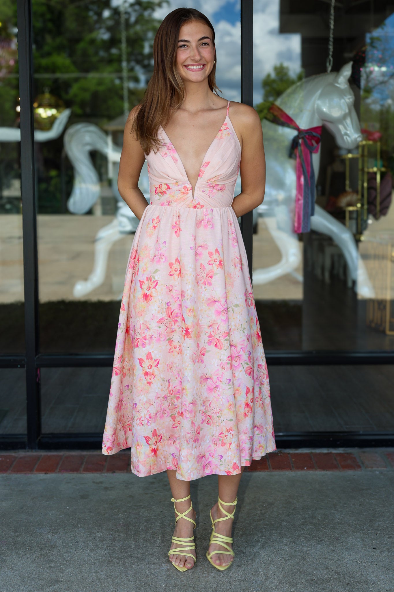 Woman wearing a floral dress standing in front of a carousel.
