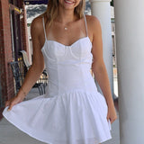 Woman wearing a white dress standing outdoors on a sunny day.