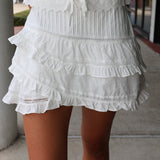 White lace skirt with ruffled layers on a person standing on a sidewalk.