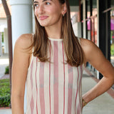 Woman wearing a striped sleeveless top and white pants outdoors.