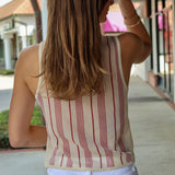 Woman wearing a striped tank top and white pants on a sidewalk.