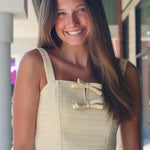 Woman wearing a light-colored top with straps and a skirt, standing outdoors.