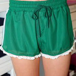 Green mesh shorts with lace trim worn by a person indoors.
