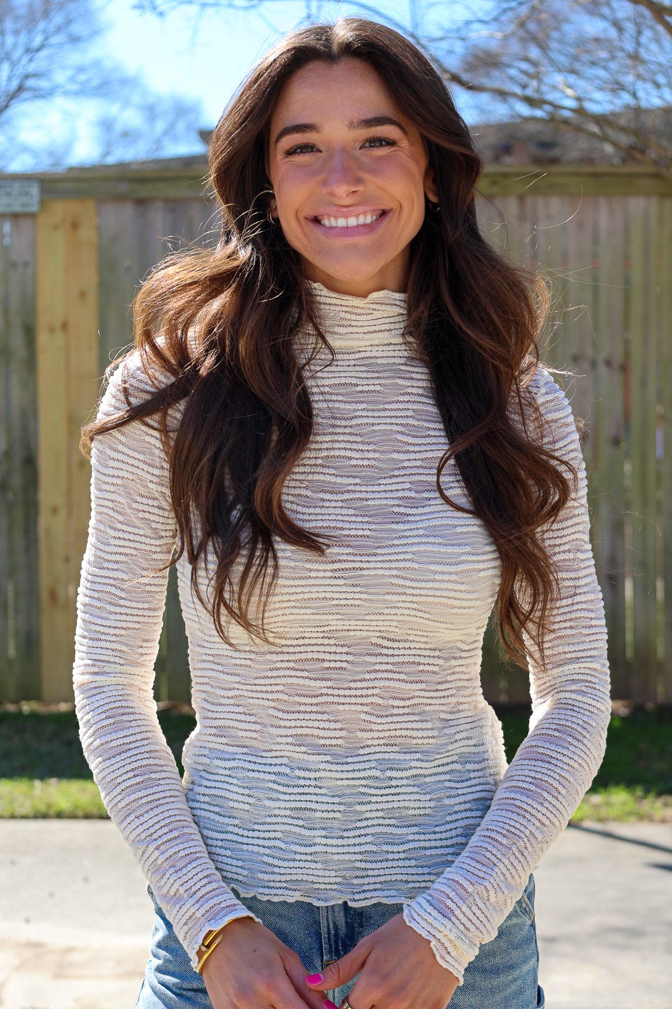 Woman wearing a white long-sleeve top with a blurred background