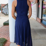 Woman wearing a blue dress standing on a sidewalk.