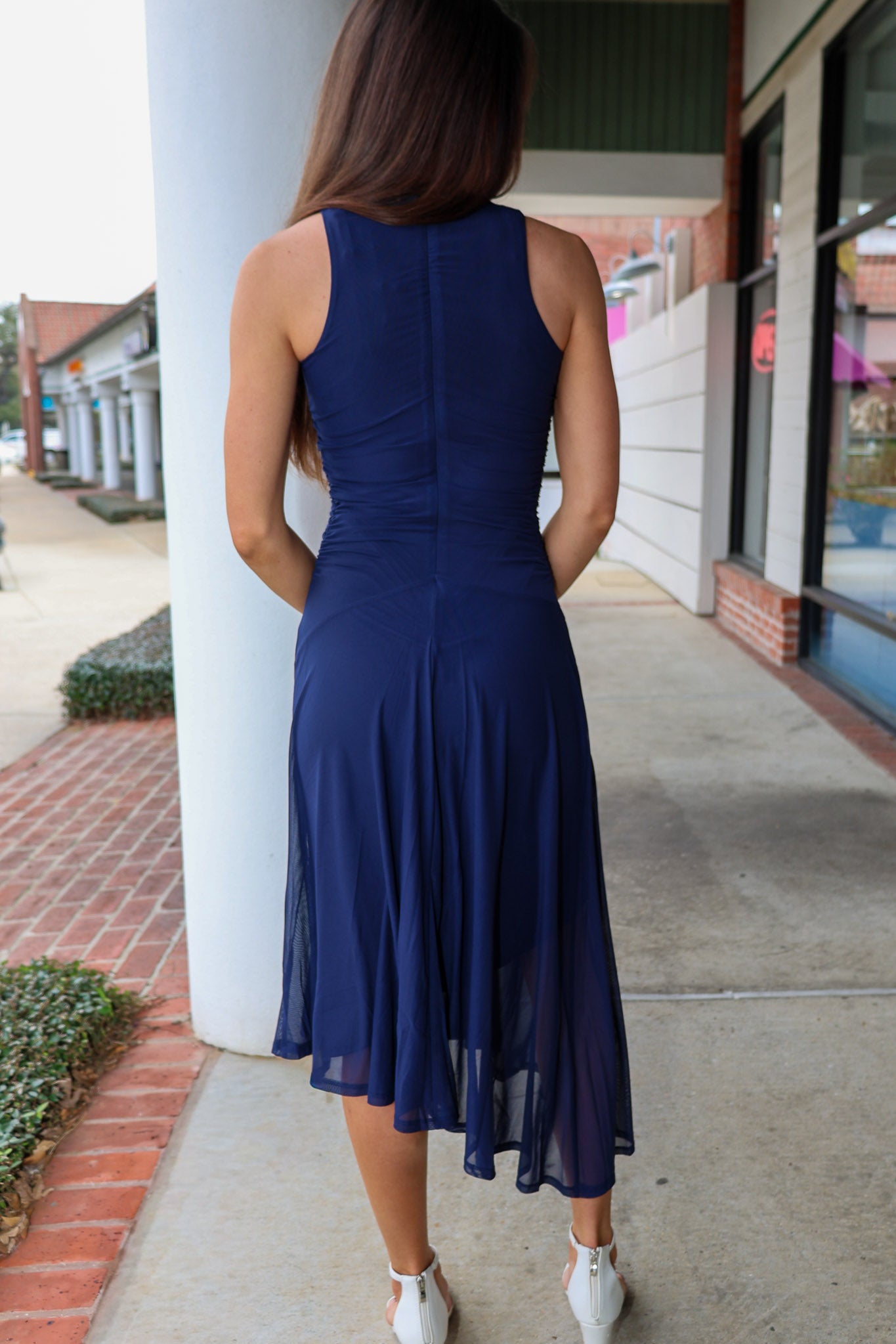 Woman wearing a blue dress standing on a sidewalk.