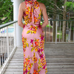 Woman wearing a pink floral dress on a wooden deck