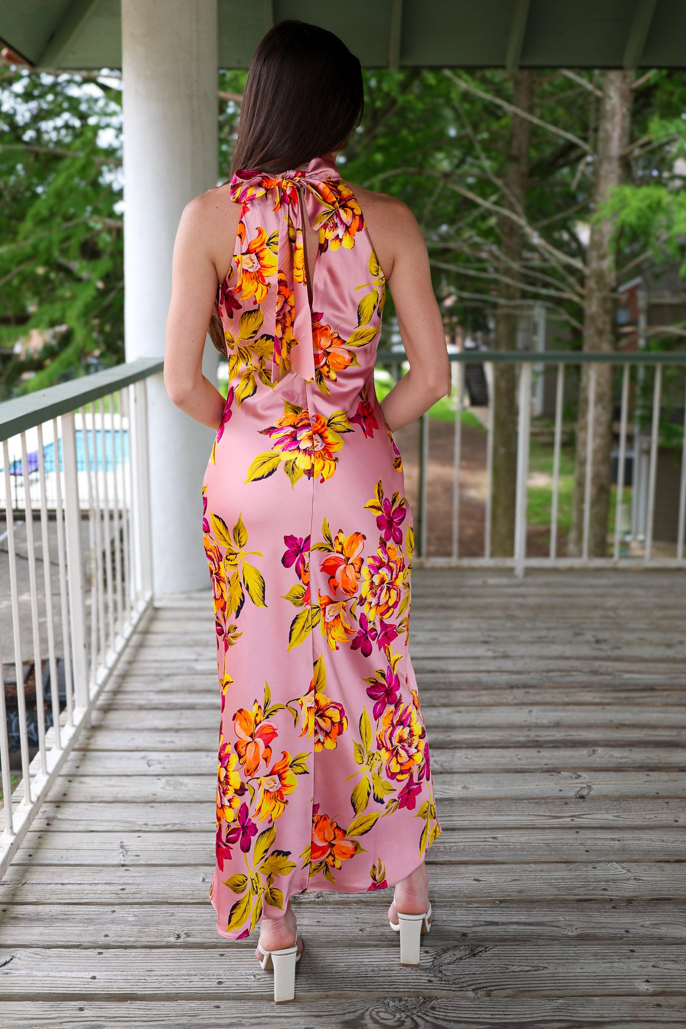 Woman wearing a pink floral dress on a wooden deck