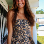 Young woman wearing a leopard print outfit standing on a sidewalk.