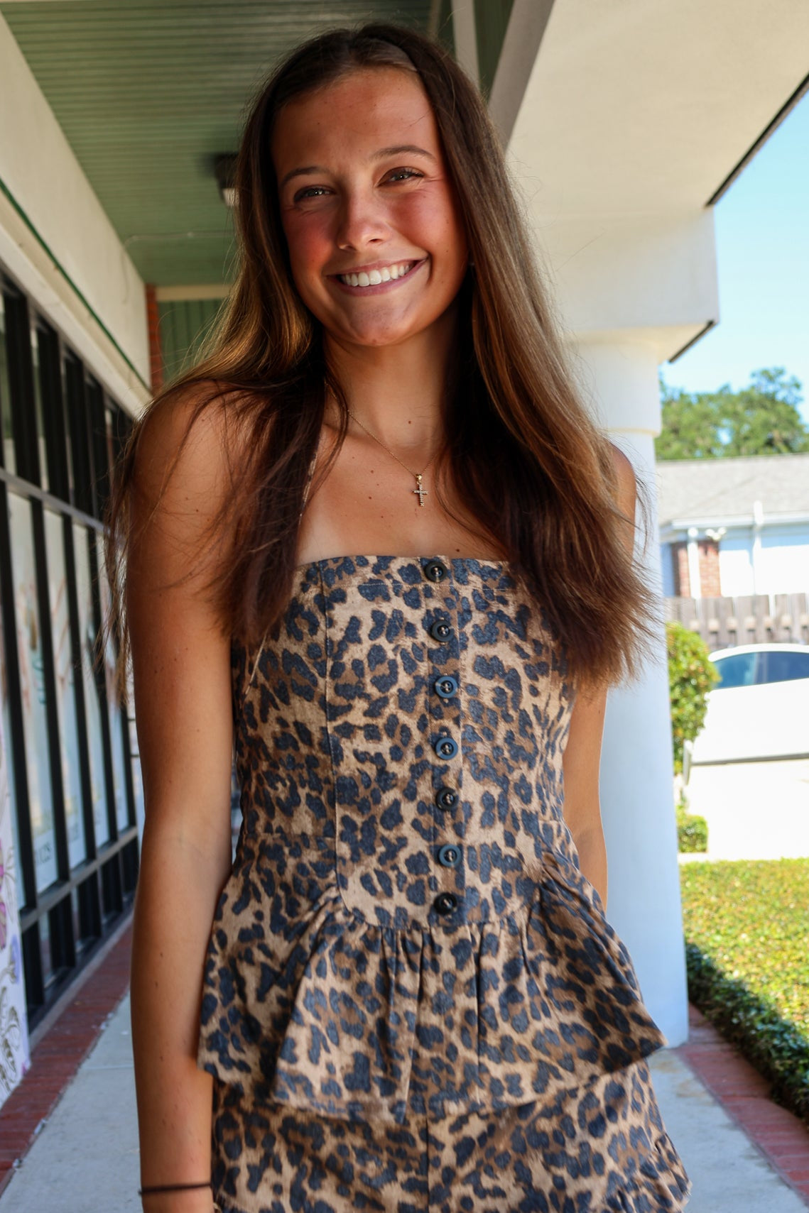 Young woman wearing a leopard print outfit standing on a sidewalk.