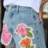 Denim skirt with floral patches worn by a person