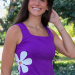 purple tank top with a large white flower graphic on the front, photographed outdoors at Rodeo Boutique.