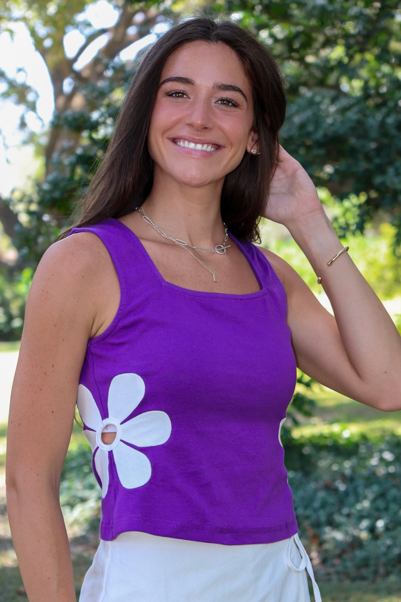 purple tank top with a large white flower graphic on the front, photographed outdoors at Rodeo Boutique.