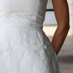 Close-up of a white textured dress with floral details.