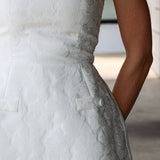 Close-up of a white textured dress with floral details.