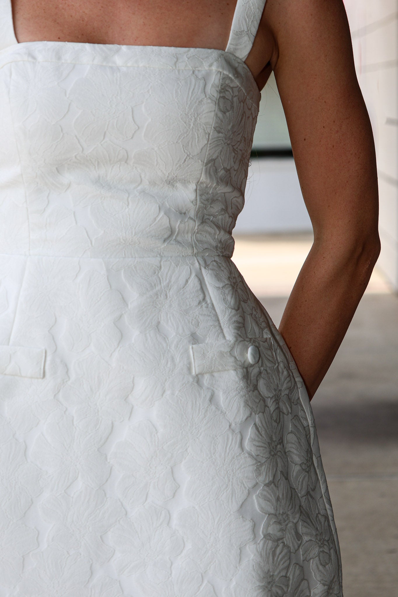 Close-up of a white textured dress with floral details.