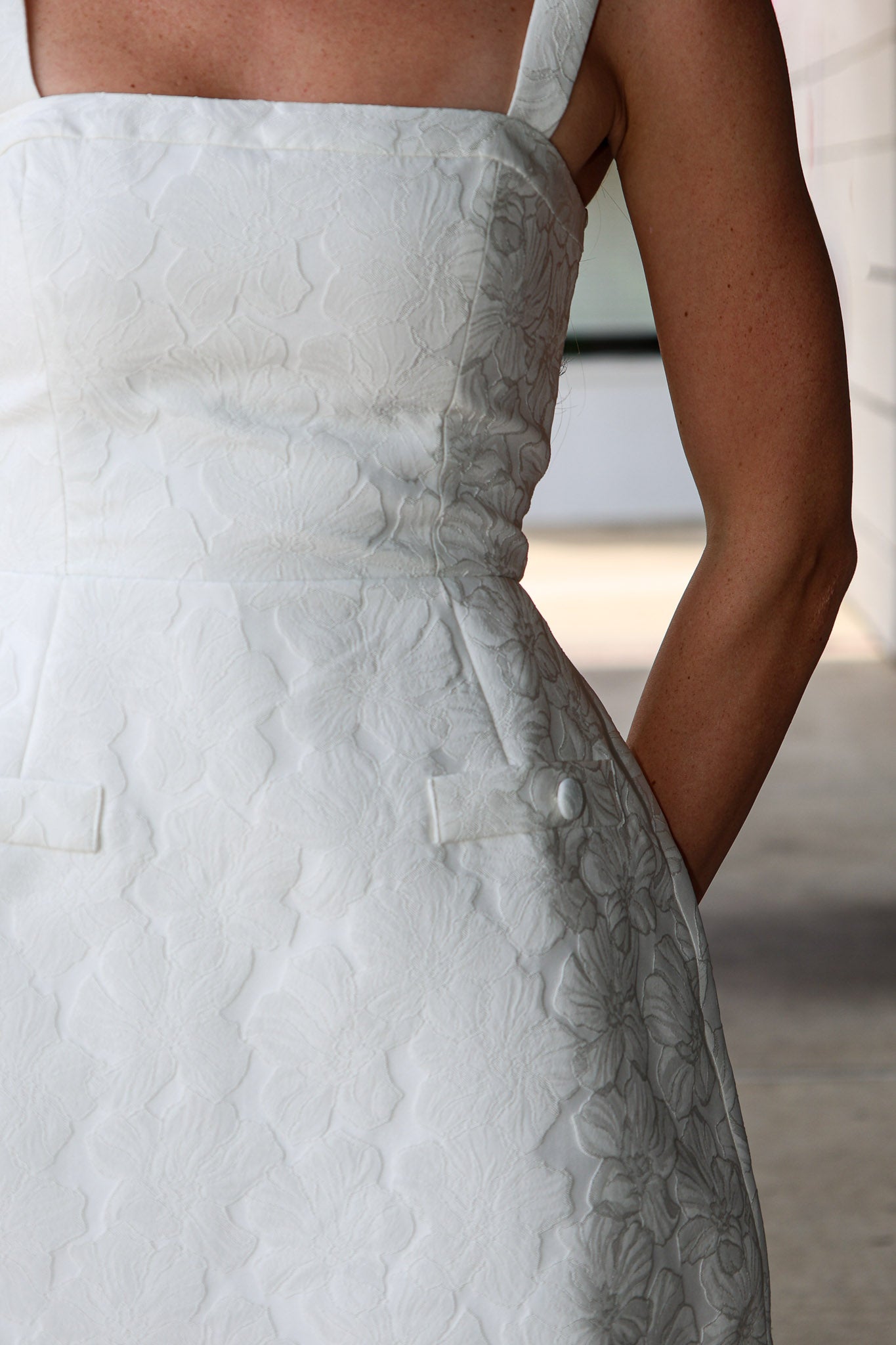 Close-up of a white textured dress with floral details.