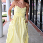 Maubois yellow dress by Deluc standing outdoors on a sidewalk.