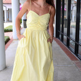 Maubois yellow dress by Deluc standing outdoors on a sidewalk.