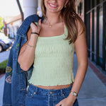 Woman wearing a light green top and blue denim skirt, holding a denim jacket.